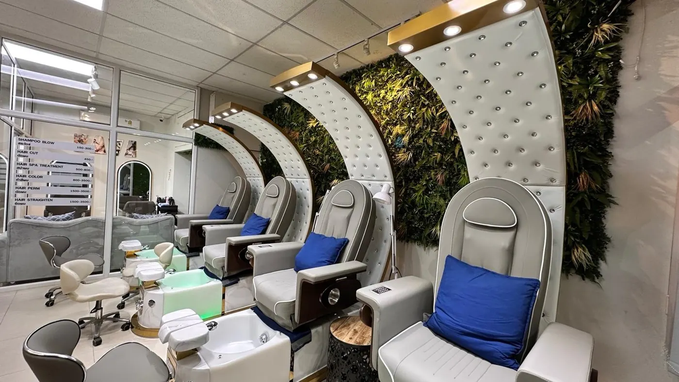 Modern nail salon with white pedicure chairs in front of a green plant wall