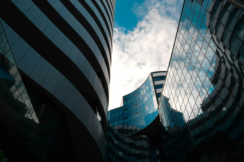 Glass office towers seen from below against a blue sky